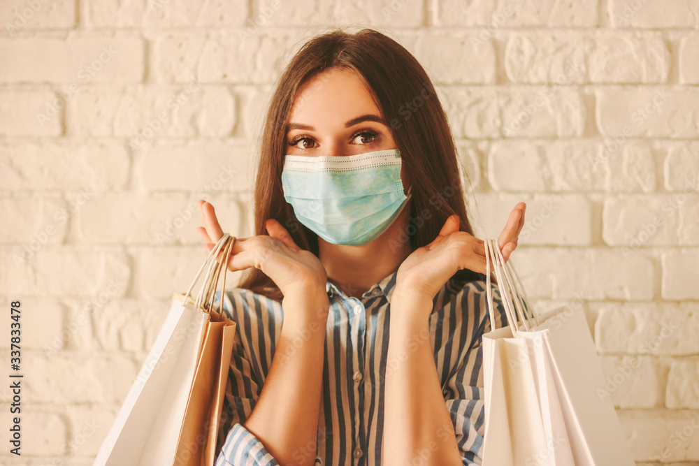 Beautiful young girl shopaholic in medical face mask and