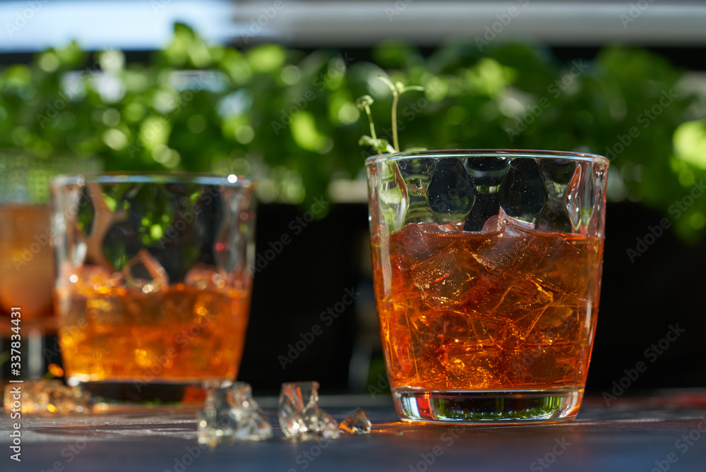 orange summer cocktail with ice on dark background. Shadows of glasses, hard sun light. orange summer cocktail with ice on dark background. Shadows of glasses, hard sun light.