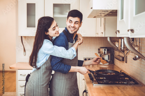 Lovely couple preparing dinner frying meat on pan