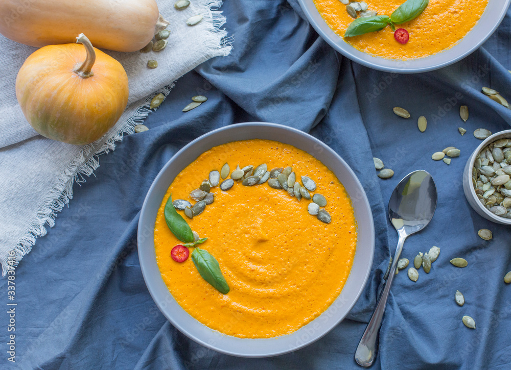 Pumpkin cream soup in ceramic plate on kitchen table Pumpkin cream soup in ceramic plate on kitchen table