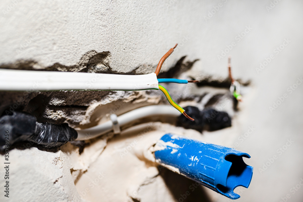 Cut single-phase cable in the wall of the house. Phase, neutral and ground wire visible.

