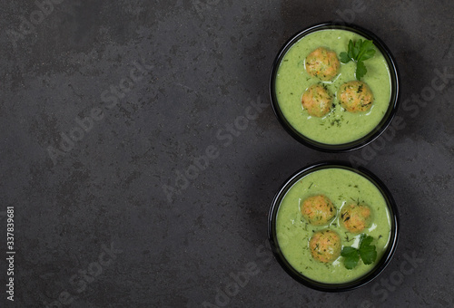 Vegan green soup-puree with meatballs in a bowl on a dark background top view