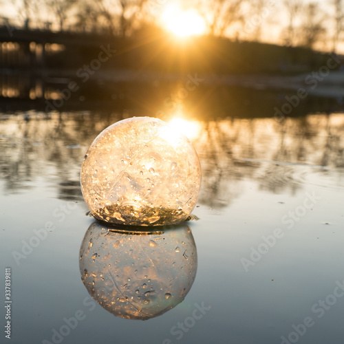 glass ball on the hand  against the backdrop of a beautiful sunset. Sunset water. Reflection in water