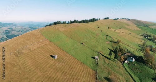 Aerial view of the beautiful mountains and the green meadow on the hill. Drone shot of a Verkhovyna village in the mountains at sunset, Carpathian Mountains, Ukraine.