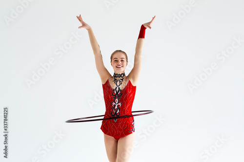 Фотография Artistic young gymnast in leotard performing with hula hoop, isolated on white