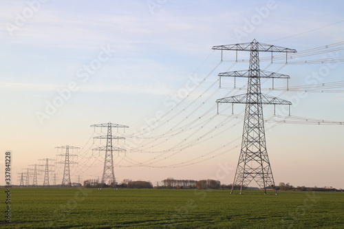 Row electricity pylon power tower landscape at sunset