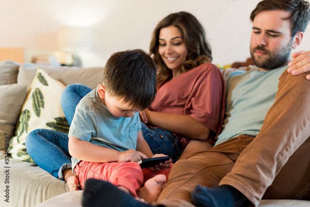 Happy couple and little boy with a smartphone at home