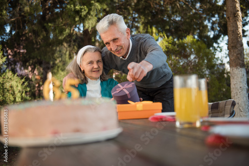 Husband hugging his wife and pointing on a birthday cake