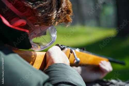 Marksman Shooting a Bolt Action Rifle in Forest - Closeup With Safety Goggles