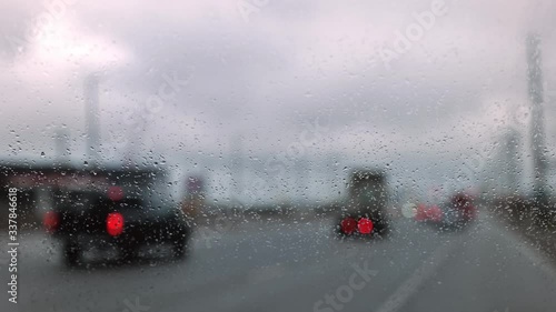 Camera focus on car wind shield and rain drop with blur traffic background. wet snow.
