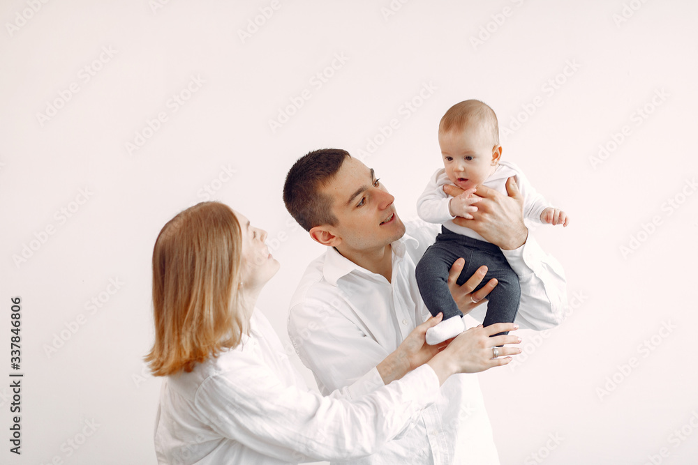 Cute family in a room. Lady in a white shirt. Woman hold child in her hands.