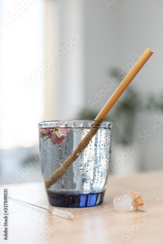 water in a glass glass with a bamboo tube and ice cubes on a table with a place for text