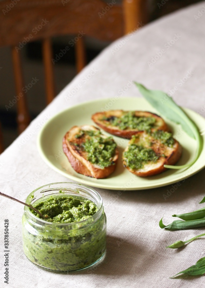 Pesto from wild garlic and fried toast from baguette on the table. Back of chair in the background. life style food Pesto from wild garlic and fried toast from baguette on the table. Back of chair in the background. life style food