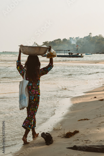 Cambodian girl carrying a basket with goods on a beach of the Koh Rong Island in Cambodia