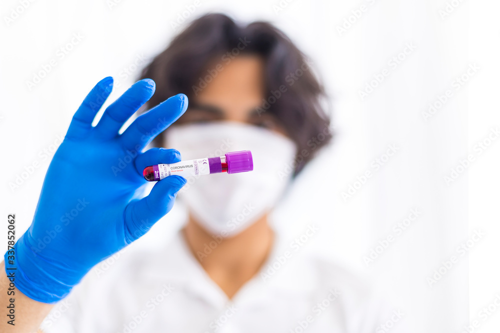 A gloved junior doctor holding a positive blood test result for coronavirus A gloved junior doctor holding a positive blood test result for coronavirus