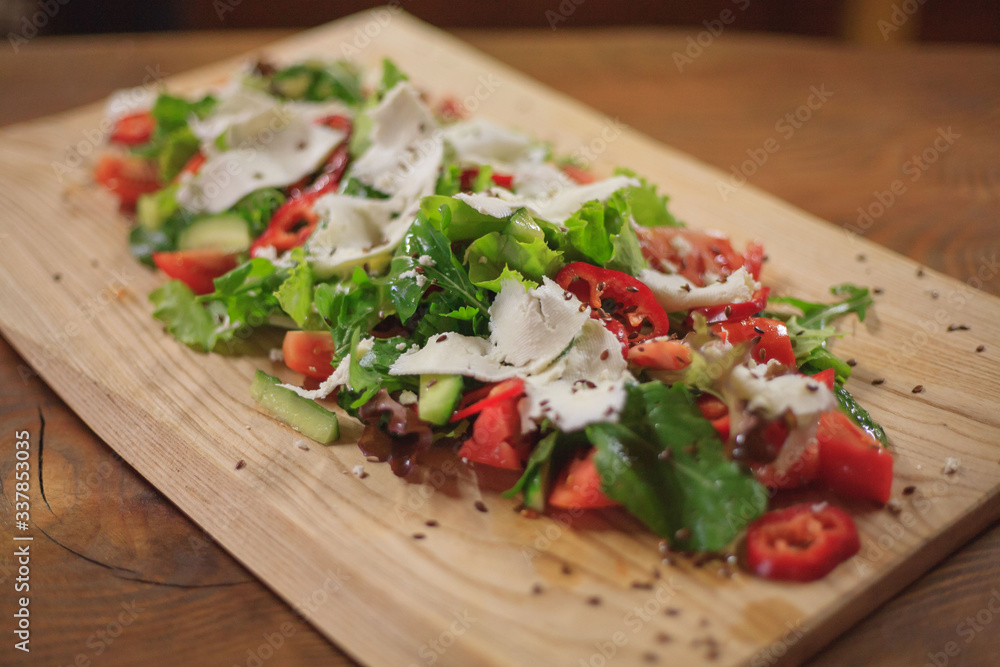 Salad on a wooden long board. Closeup on a wooden table Salad on a wooden long board. Closeup on a wooden table