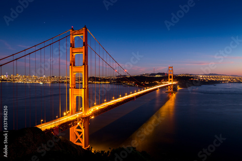 Fototapeta Naklejka Na Ścianę i Meble -  Sunset over the Golden Gate Bridge with the skyline of San Francisco, California in the background.