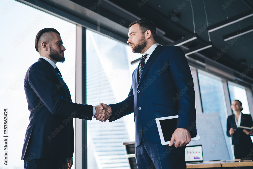Pensive businessman shaking hand of partner Pensive businessman shaking hand of partner