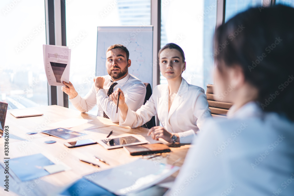 Focused businesspeople analysing charts and using tablet at meeting in conference room Focused businesspeople analysing charts and using tablet at meeting in conference room
