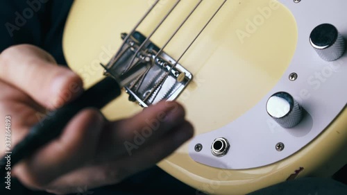 CU: professional musician connects quarter-inch jack with output on white pick guard of bass guitar extreme close view photo