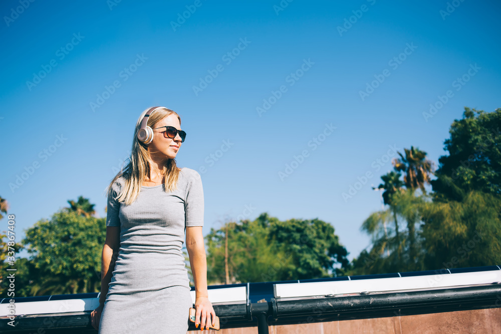 Blond woman listening to music in park