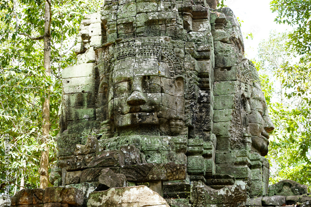 Angkor Wat, a sculpture with the faces of the gods directed to the four cardinal directions, stones turned green from time to time, enlarged plan      