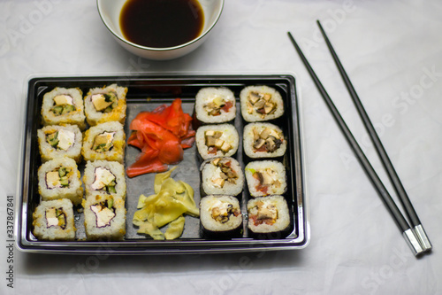 japanese cuisine different rolls with black chopsticks red pickled ginger wasabi sauce and soy sauce on the table