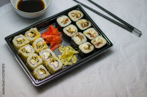 japanese cuisine different rolls with black chopsticks red pickled ginger wasabi sauce and soy sauce on the table