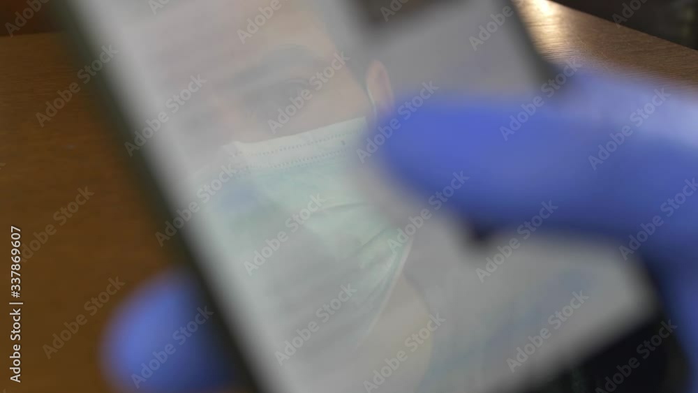 Man in Surgical Mask Scrolling Virus News on Smartphone in Blue Gloves Man in Surgical Mask Scrolling Virus News on Smartphone in Blue Gloves