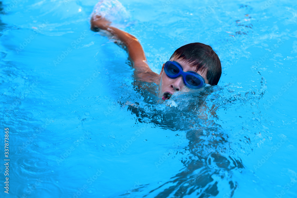 Little boy athlete swims in the pool by the crawl. The concept of training and children's sports