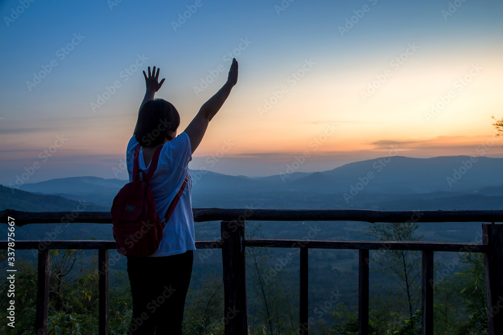 Fototapeta premium Asian women tourist happy freedom during dramatic sunset at Khao Yai,Nation park of Thailand ,Concept of outdoor camping adventure