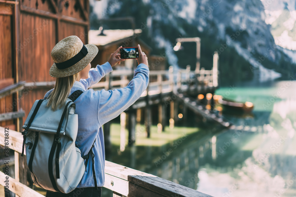 Female traveler taking picture of nature from pier