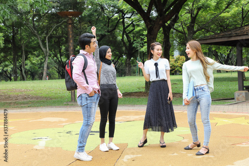 Young asian malay chinese man woman outdoor park walk stand study talk discuss point laptop file book backpack mingle fun