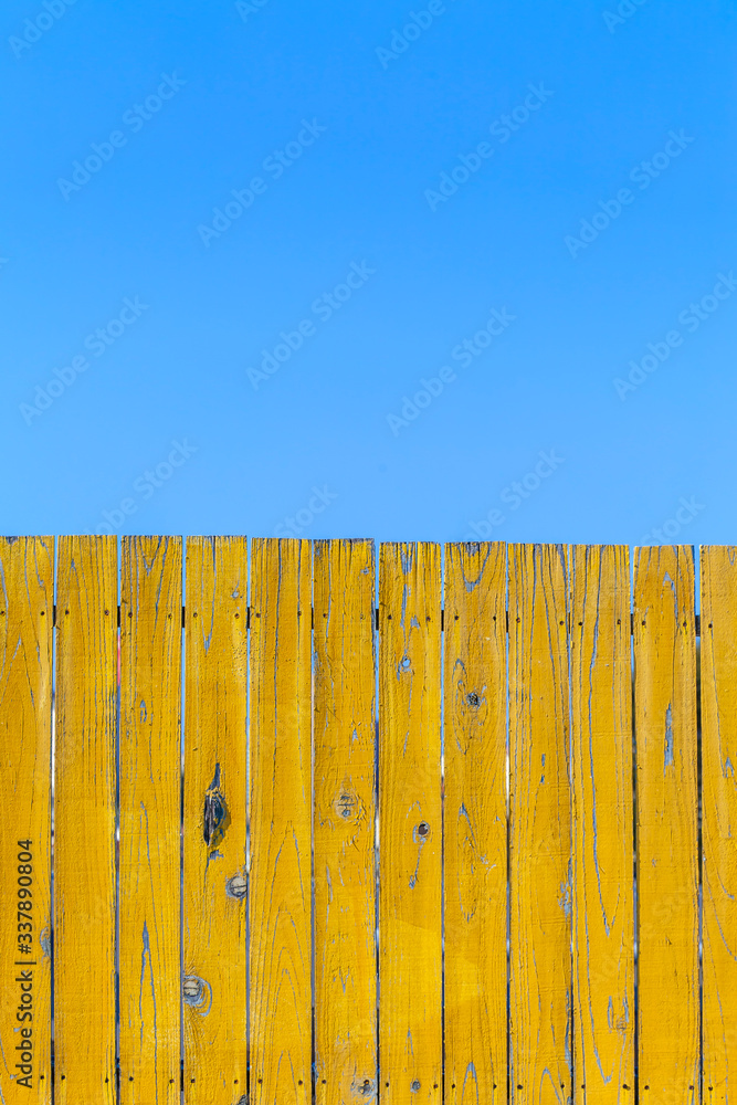 Fototapeta premium 青空と黄色の古びた板塀。背景用素材