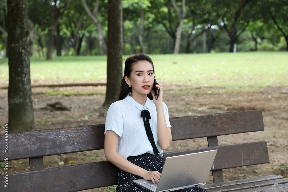 Young asian chinese woman outdoor on park bench use laptop computer think read look happy wonder smile front talk on phone Young asian chinese woman outdoor on park bench use laptop computer think read look happy wonder smile front talk on phone