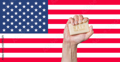 Caucasian male hand holding soap with words: Wash Your Hands against an American flag background photo