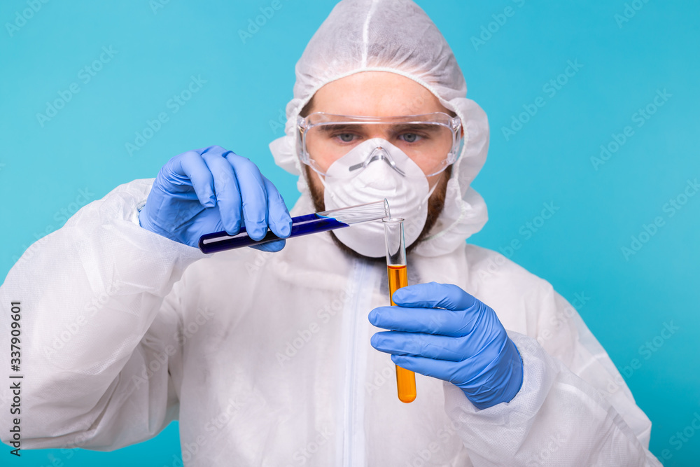 Covid-19, Vaccine development, pandemic, outbreak and coronavirus concept - Man scientist dressed personal protective equipment holding a test tube and does a chemical experiment. Covid-19, Vaccine development, pandemic, outbreak and coronavirus concept - Man scientist dressed personal protective equipment holding a test tube and does a chemical experiment.