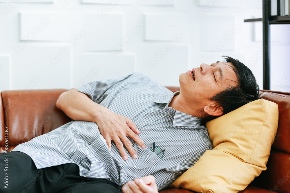 An elderly man is suffering from chest pain on Chofa in the house. An elderly man is suffering from chest pain on Chofa in the house.