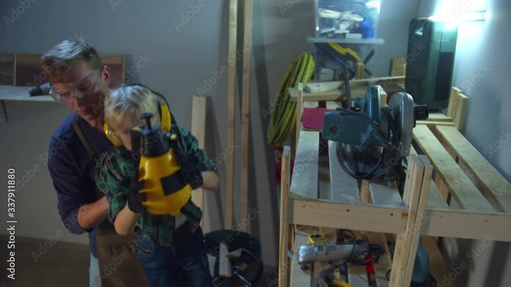 The boy is trying to reach the top shelf, and dad helps him The boy is trying to reach the top shelf, and dad helps him