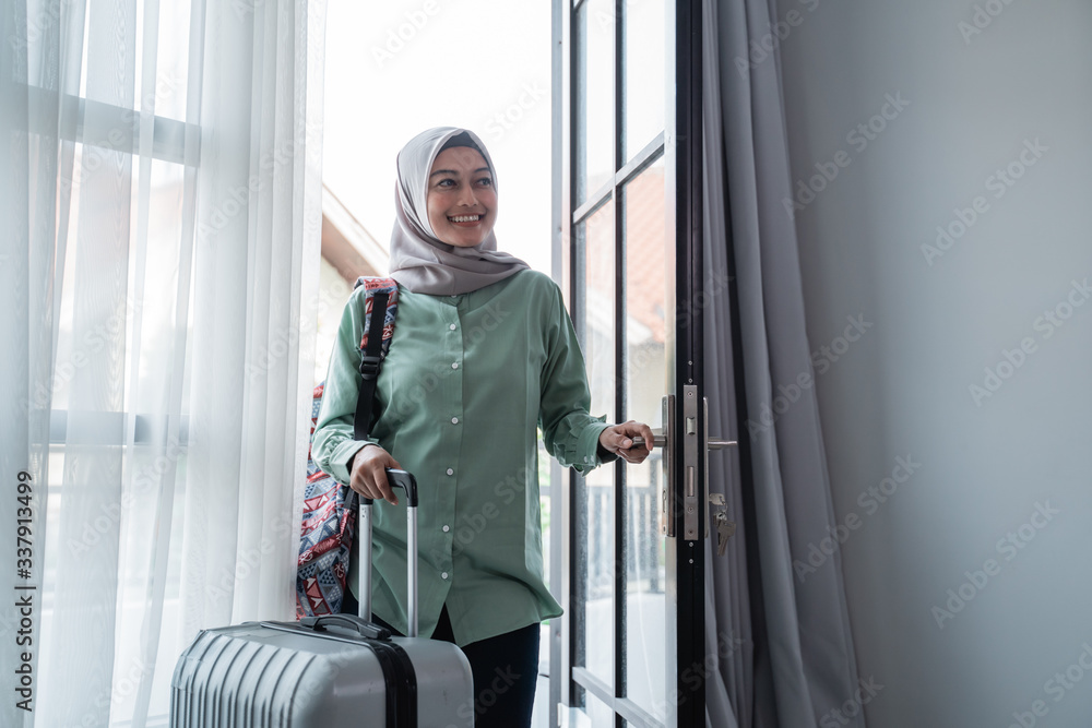 muslim woman traveler opened the door entrance with her bag and suitcase go home after traveling muslim woman traveler opened the door entrance with her bag and suitcase go home after traveling