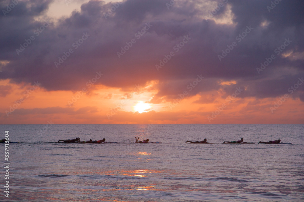 sunrise behind surfers 