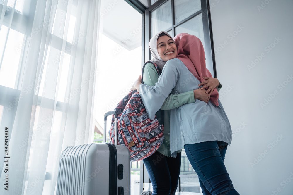 veiled woman hugs her sister when meeting at the door of the house after being away for a long time veiled woman hugs her sister when meeting at the door of the house after being away for a long time