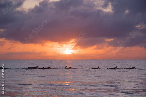 sunrise behind surfers 
