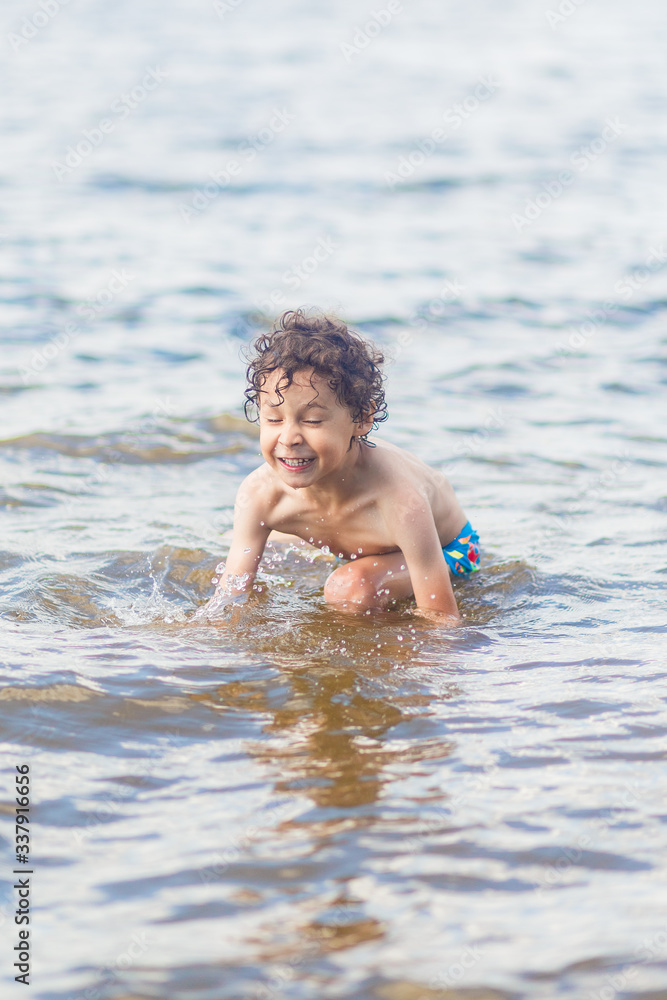boy in blue swimming trunks having fun in the lake in summer