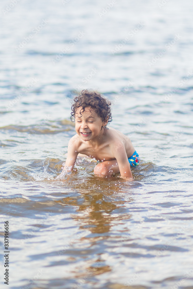 boy in blue swimming trunks having fun in the lake in summer boy in blue swimming trunks having fun in the lake in summer