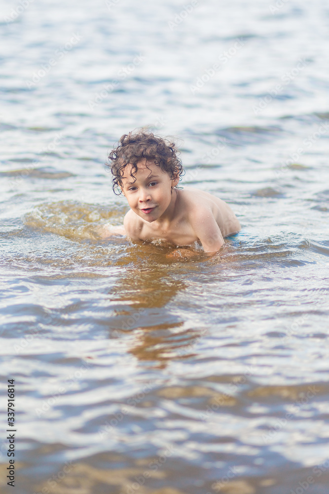 boy in blue swimming trunks having fun in the lake in summer boy in blue swimming trunks having fun in the lake in summer