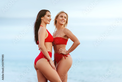 Two amazing tanned girls on the beach, blonde and brunette, long hair, perfect figures. © Margo Basarab