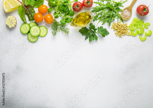 Raw fresh ingredients for vegetarian salad:cherry tomatoes,arugula leaves,parsley,cucumber,lemon,garlic,olive oil,celery and sea salt on light background.