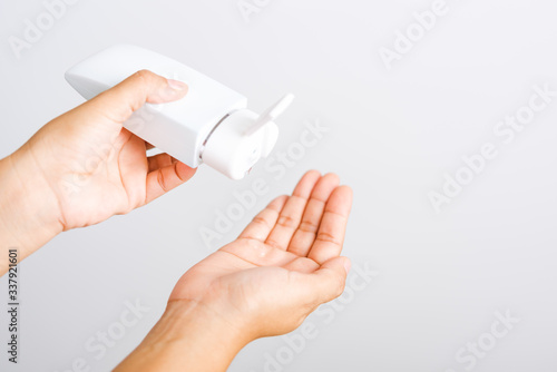 young woman applying drop dispenser sanitizer alcohol gel on hand