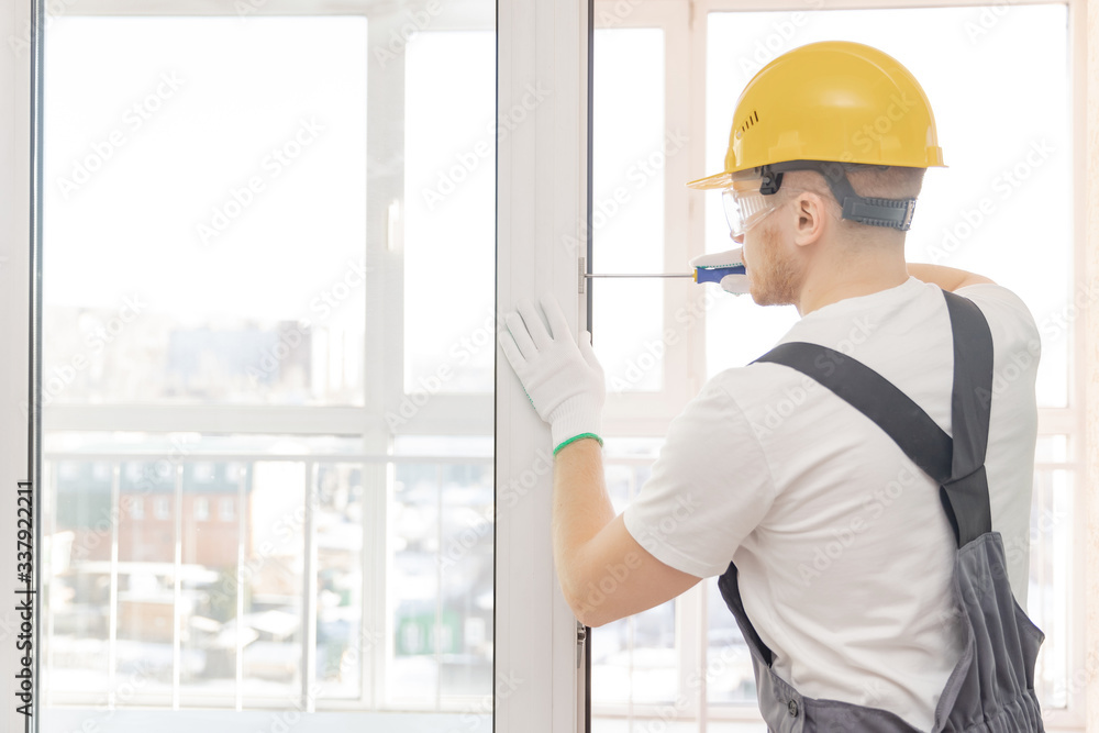 Worker man installs plastic windows white lock and seal adjustment Worker man installs plastic windows white lock and seal adjustment